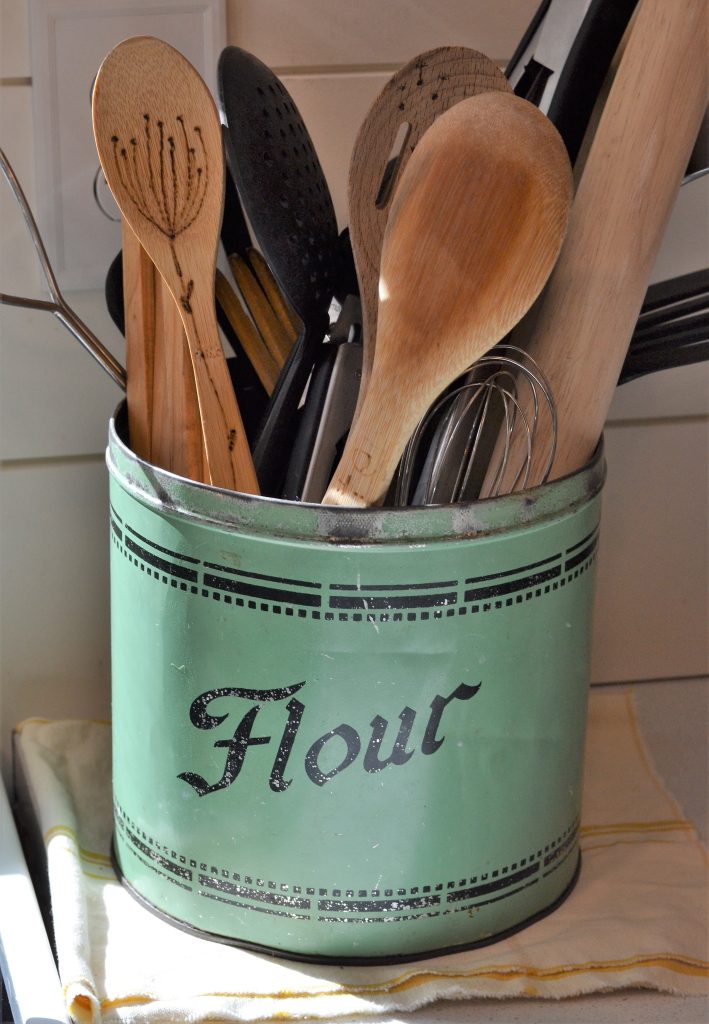 vintage green color farmhouse decor flour can being used as a utensil holder