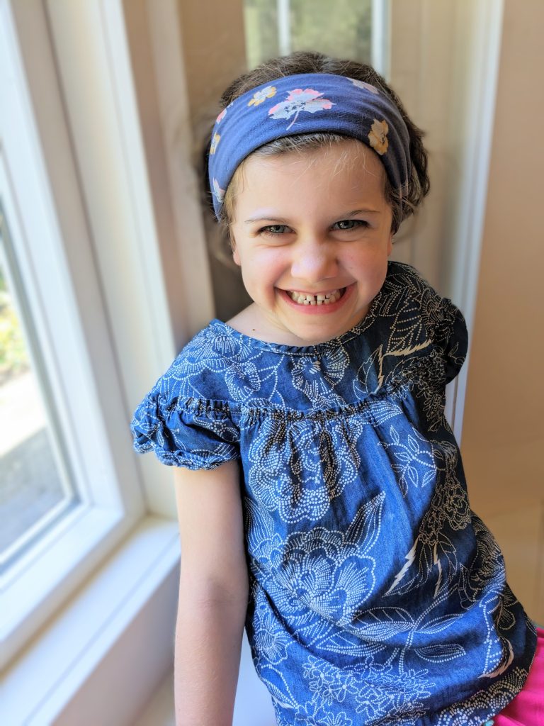 young girl smiling and wearing a headband made from leggings