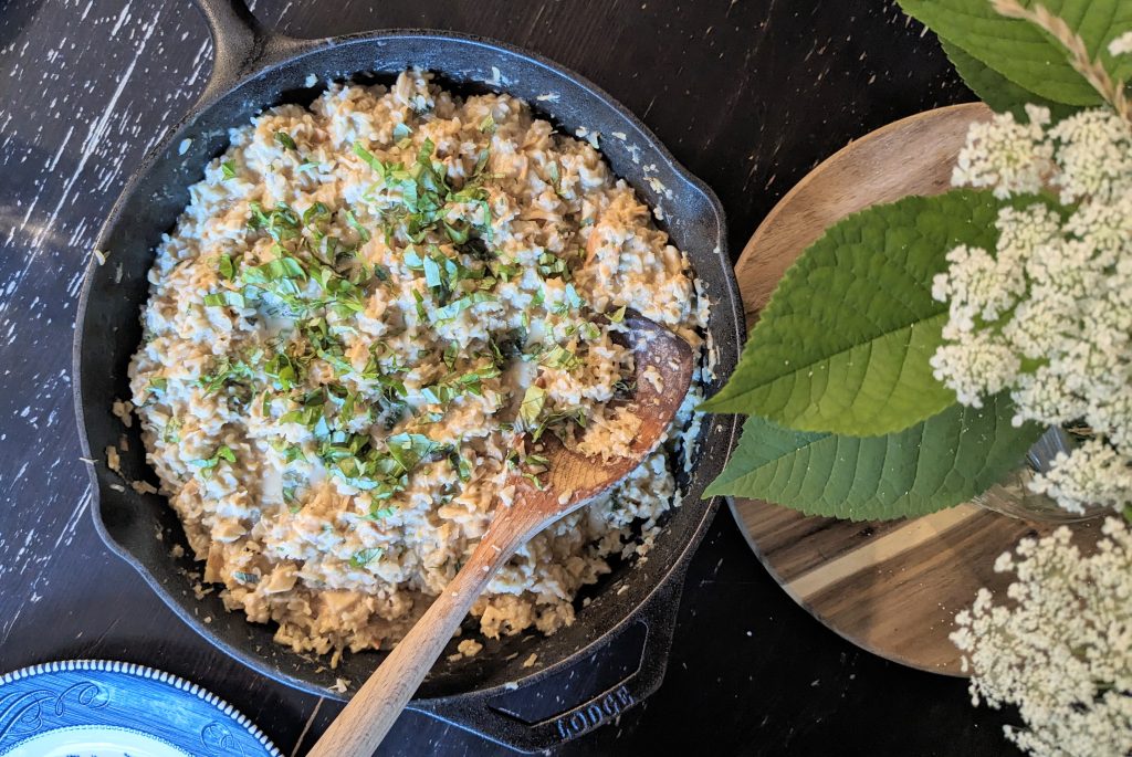 a cast iron skillet of a rice and chicken dish sprinkled with herbs