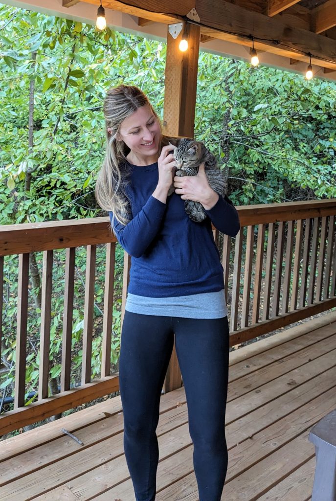 girl wearing sweater and leggings holding a kitten